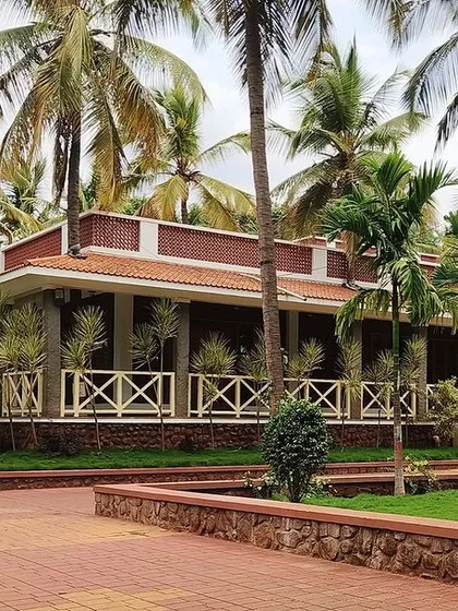 A wider perspective of the "Grid in the Grove" farmhouse, showing how the long, low structure is beautifully situated among the palm trees, creating a seamless integration with the landscape.
