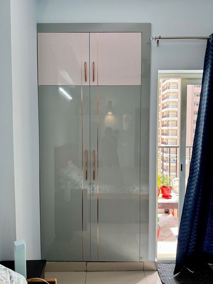A two-tone wardrobe in grey and white high-gloss finish, with elegant rose-gold handles, perfect for a modern bedroom.