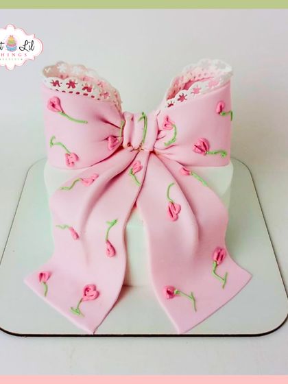 A cake that's pretty in pink and wrapped with a bow. This design features a large, delicate pink bow with tiny tulip details.
