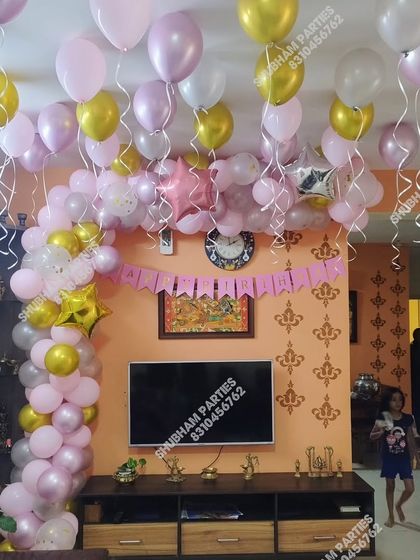A cheerful home birthday decoration with pink, white, and gold balloons.