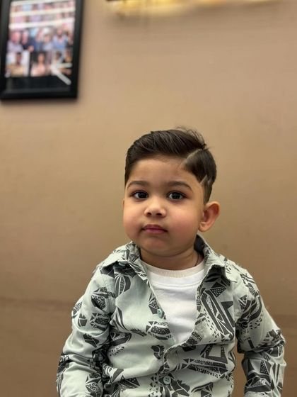 A frontal view of a cute little boy with his new, sharp haircut, looking very dapper.