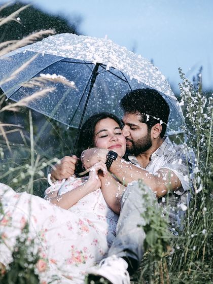 A romantic kiss on the cheek, with a couple huddled under an umbrella during a simulated snow or rain shower.