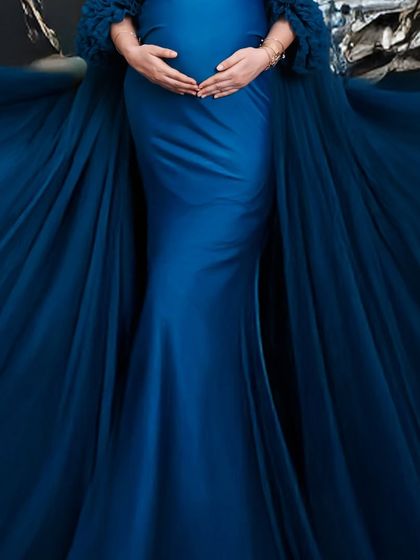 A close-up detail shot of a dramatic blue maternity gown. The focus on the rich fabric and the baby bump creates an abstract and artistic image.