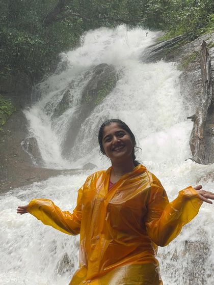 A trekker in a yellow poncho enjoying the downpour at Hidlumane Falls.