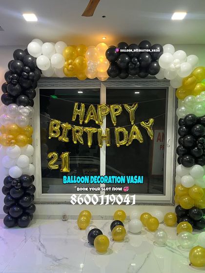 A 21st birthday balloon arch in black, white, and gold. The "Happy Birthday" foil letters are a central feature of this home setup.