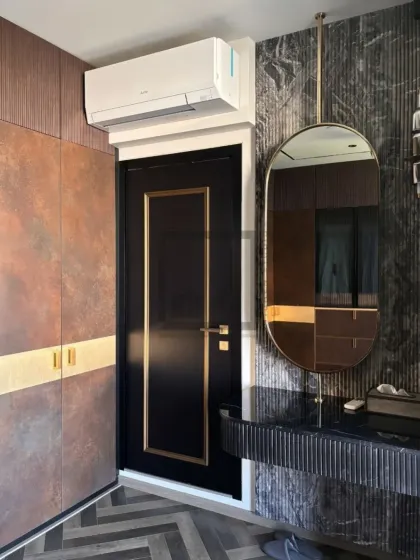 This image shows how we design around existing architectural elements, like doors and air conditioning units, to create a fully integrated look. The wardrobe, door, and vanity all share a cohesive design language with matching gold accents.
