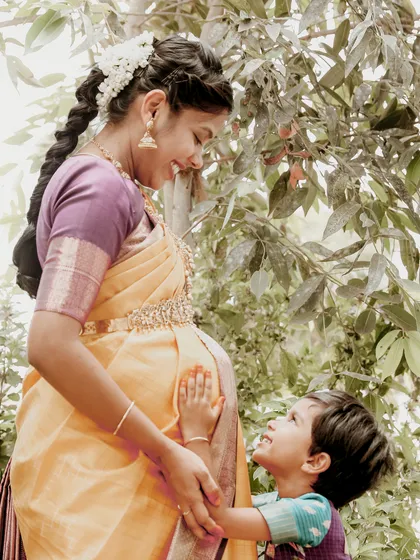 The bond between a mother and child is precious. Here, an older sibling-to-be lovingly touches his mother's baby bump in a beautiful, sunlit outdoor setting.