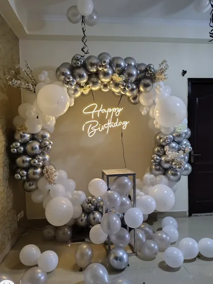 A classic silver and white balloon ring with a neon sign, perfect for an elegant birthday or anniversary party at home.