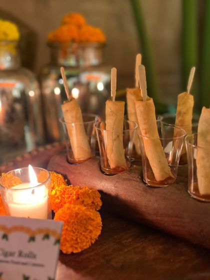 Crispy cigar rolls served in glasses on a wooden platter, illuminated by candlelight. This is a simple yet elegant appetizer, perfect for kicking off a festive Diwali celebration.