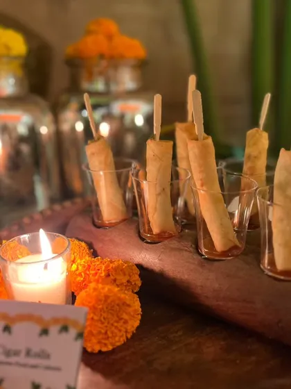 Crispy cigar rolls served in glasses on a wooden platter, illuminated by candlelight. This is a simple yet elegant appetizer, perfect for kicking off a festive Diwali celebration.