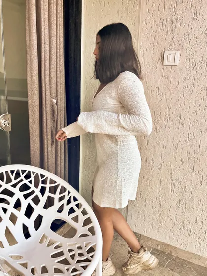 A side view of the white ribbed dress. The simple design and soft fabric make it a versatile piece for any casual occasion.