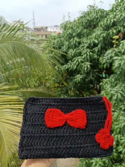 A black crochet pouch with a contrasting red bow. This design is bold and stylish, and like all my items, can be customized.
