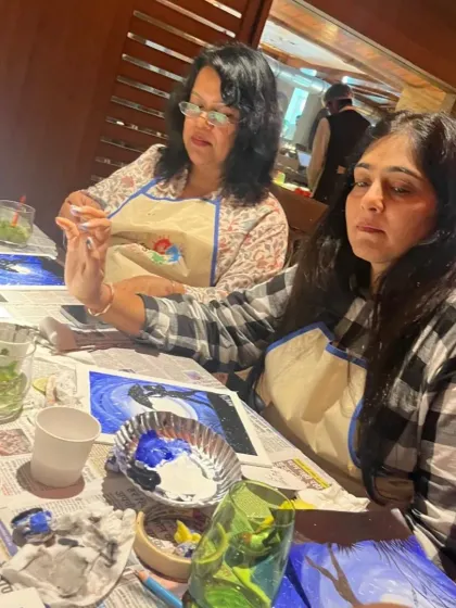 Two friends concentrating on their artwork during a kitty party. Art is a wonderful way to unwind and focus, offering a peaceful break from daily routines.