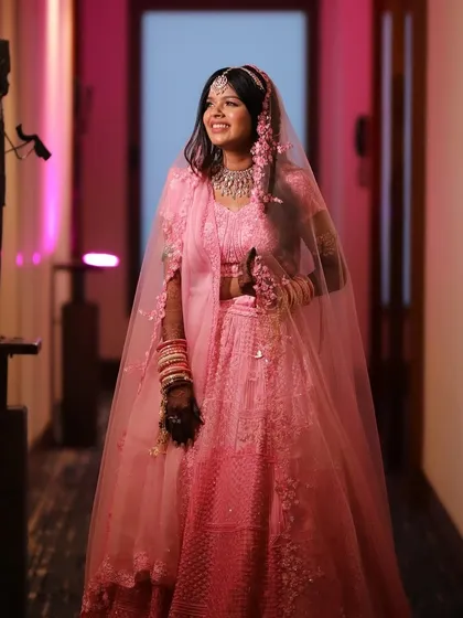 A candid shot of the bride walking down the hallway, her pink lehenga and radiant smile lighting up the space. The makeup is designed to look fresh and beautiful from every angle.
