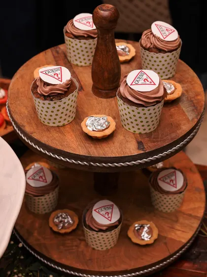 Custom-branded cupcakes for the GUESS store launch. These chocolate cupcakes are topped with the iconic GUESS logo, adding a personalized and stylish touch to the event.
