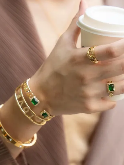 A close-up of our gold and emerald collection, featuring the emerald stone ring and spike spiral ring. It's a sophisticated look, perfect for the office or a coffee date.