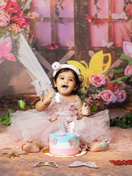A full shot of the birthday girl enjoying her cake in the beautiful butterfly garden setup.