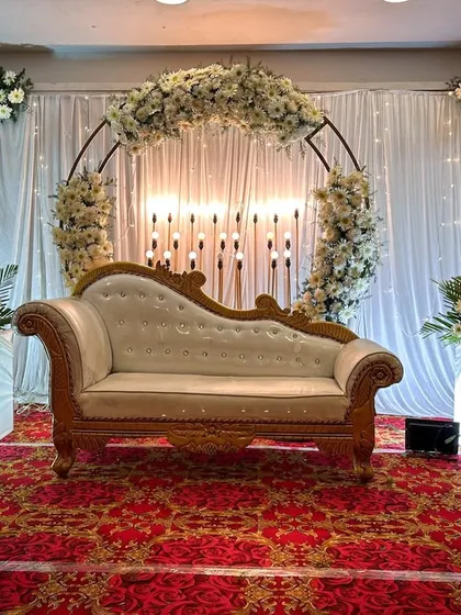 An elegant and minimalist engagement stage. The clean white floral arch, soft drapery, and warm lighting create a romantic and sophisticated ambiance for celebrating your new beginning.