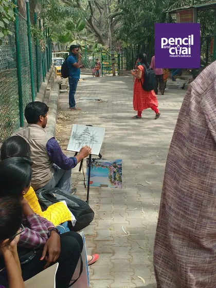 An instructor sets up his easel on a quiet pathway, demonstrating landscape sketching techniques for the group.