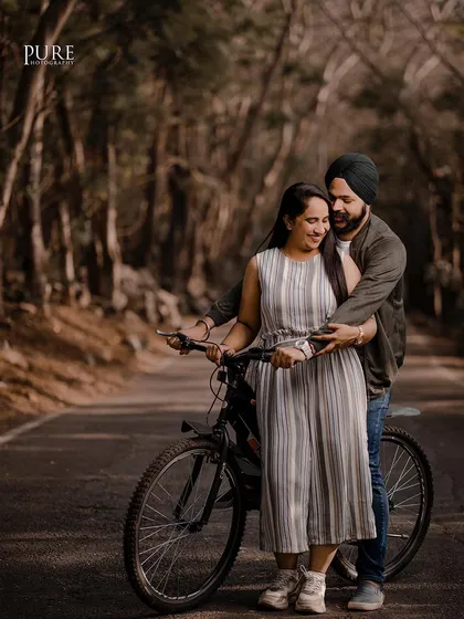 A fun and candid moment with a bicycle on a tree-lined road. This shot from Karan and Simarpreet's pre-wedding session is playful, natural, and full of personality.