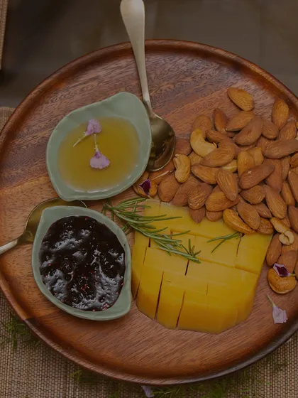 A simple yet elegant platter of sliced mango, almonds, honey, and jam. We believe in using the finest ingredients to create moments of pure, simple luxury.