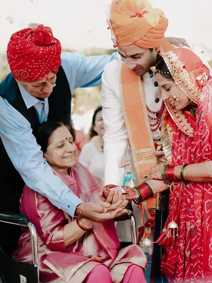 A bride and groom share a moment with an elder family member in a wheelchair during their wedding ceremony. This image is a testament to family bonds and the inclusion of all loved ones in the celebration.