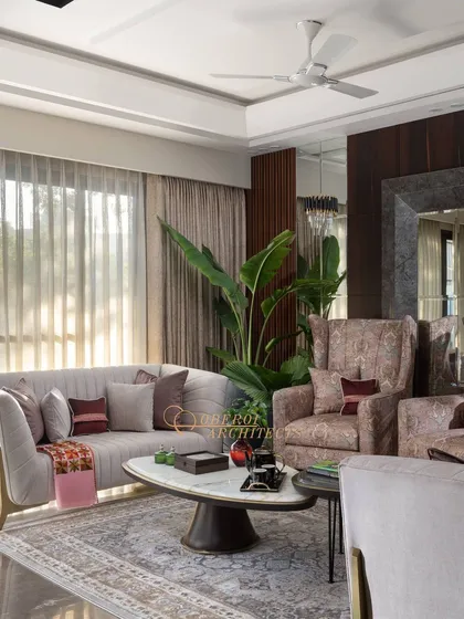 This living room design features cream accent sofas and cozy armchairs, adorned with lush green plants for a refreshing touch.