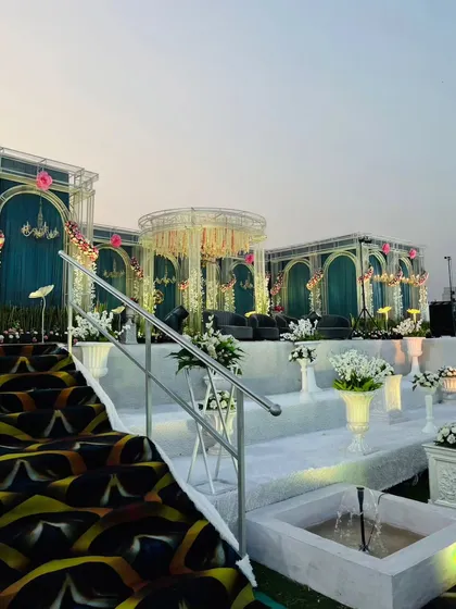 This angle highlights the central ceremony mandap, flanked by palatial arches. The combination of the modern patterned carpet and classic architectural elements creates a unique fusion style for this grand wedding.