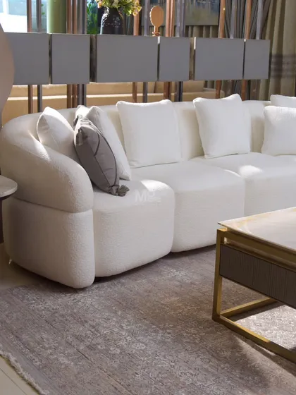Meet the Aether Sofa, designed to be a journey in relaxation. Its gracefully curved silhouette and deep, generous cushions create a cocoon of pure comfort. We chose a high-quality ivory bouclé for its soft, looped texture, which adds a touch of cozy sophistication and serene, timeless charm to any living space.