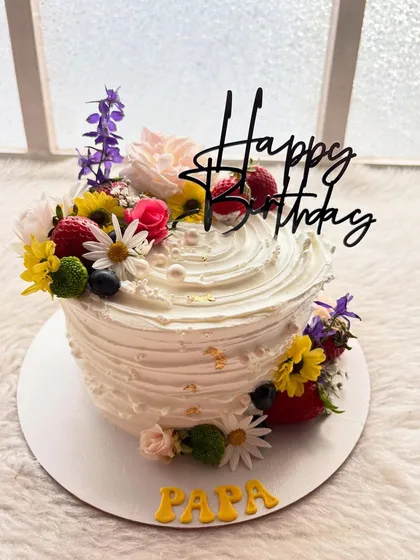 A vibrant cake perfect for a father's birthday. It's topped with a beautiful arrangement of fresh, colorful flowers and berries for a natural, garden-fresh look.