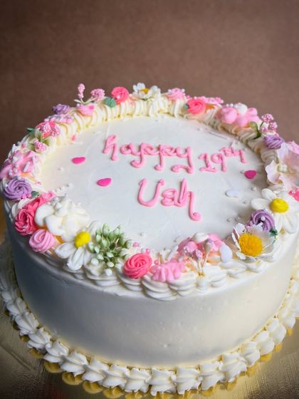 A lovely and simple birthday cake for Ushma's 19th. The white buttercream is decorated with a delicate wreath of tiny, colorful hand-piped flowers.
