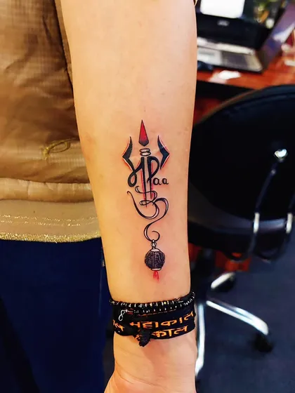 A variation of our popular 'Maa-Paa' Trishul design, this tattoo uses a touch of red to highlight the sacred weapon. It’s a beautiful tribute to parents, intertwined with spiritual strength.