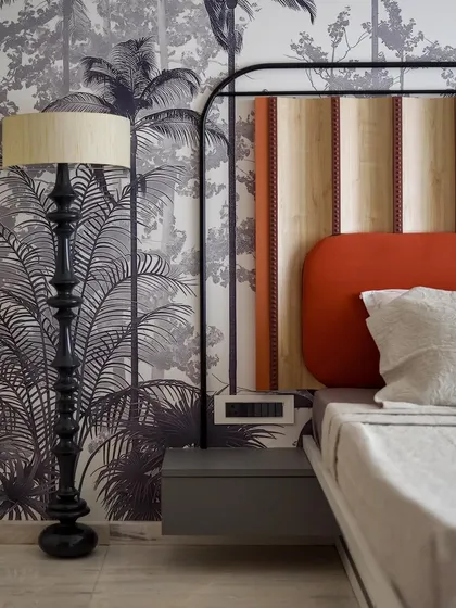 The unique floor lamp in the master bedroom was handcrafted on-site with a turned wooden design. Its dark, sculptural form stands out beautifully against the tropical wallpaper.