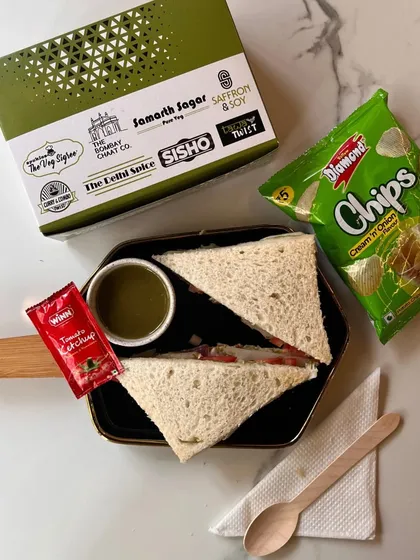 Perfect for a lighter option, this snack box features a fresh vegetable sandwich with a side of mint chutney. Paired with chips and ketchup, it's a simple yet popular choice for corporate meetings and school events.