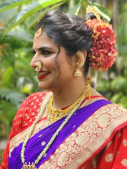 A portrait of the dimply beauty. Her smile is infectious, and the traditional makeup with a bold red lip and floral bun completes her perfect bridal look.