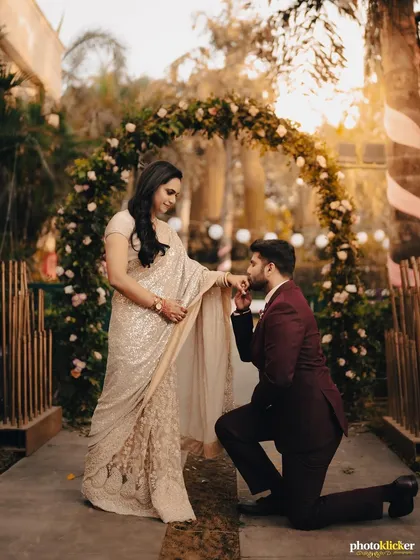 A classic romantic gesture, beautifully framed. This engagement photo captures the groom kneeling before his bride under a floral arch, a perfect shot for your save-the-dates.