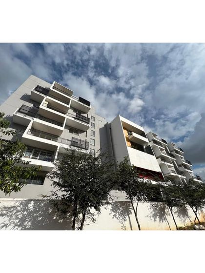 The facade of "The Treehouse" apartments under a dramatic sky. The staggered balconies create a dynamic play of light and shadow across the building's surface.