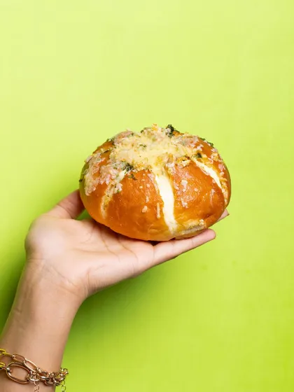 A single, perfect Korean Cream Cheese Bun, showcasing its golden-brown crust and cheesy topping. It's the ultimate savoury snack.