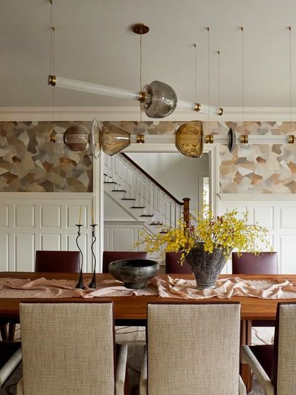 A customized Luna Kaleido chandelier hangs above a long dining table, its unique composition of colored glass beads adding a bespoke touch. This view highlights how the modular system can be adapted to create a one-of-a-kind centerpiece for formal dining.