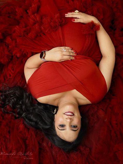 A joyful overhead shot. Lying in a bed of red ruffles, the mom-to-be's happy expression is the focus of this vibrant and creative portrait.