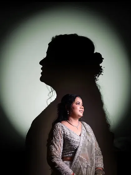 An artistic silhouette portrait of a bride against a spotlight, creating a dramatic and elegant look.