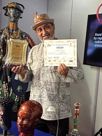 Receiving an award for my contributions to eco-art. Behind me stands my 'Avatara' mannequin, showcasing the kind of work that has earned this recognition.