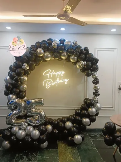 A sleek black and silver balloon ring with a neon 'Happy Birthday' sign for a 25th birthday.