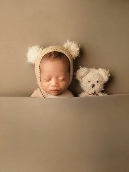 A minimalist composition focusing on the newborn and his teddy bear friend. This style of newborn photography draws all the attention to the baby's peaceful expression.