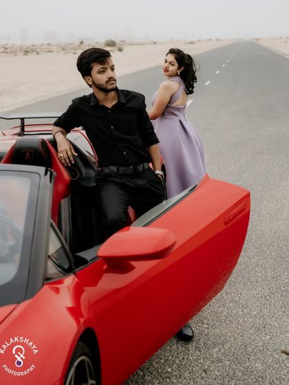 A stylish shot of the couple with the red sports car, focusing on their confident poses and the luxury aesthetic.