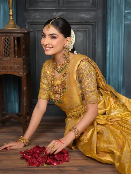 A full-length shot of the bride seated gracefully, surrounded by flower petals. This image captures the complete South Indian bridal look in all its glory.