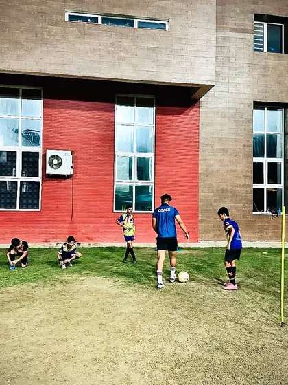 Our U13 Elite Squad in action during a night session. This image shows players working on agility and ball control drills with marker poles under the guidance of a coach.