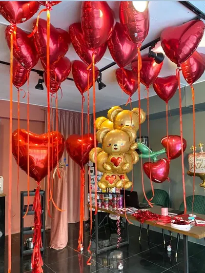 We are ready for Valentine's Day. This room setup is filled with red heart-shaped helium balloons and a giant teddy bear made of gold foil balloons.