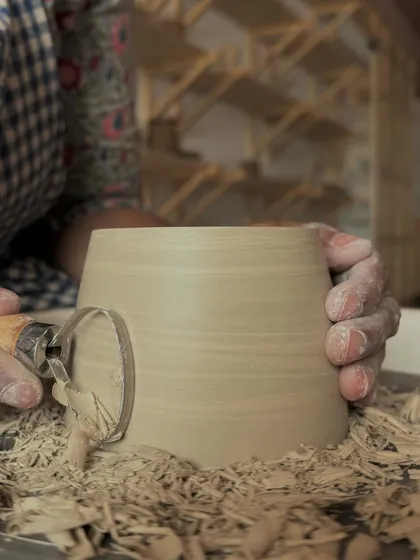 Molded from the earth, shaped by the soul. A close-up of the trimming process, where shavings of clay fly off the spinning pot.