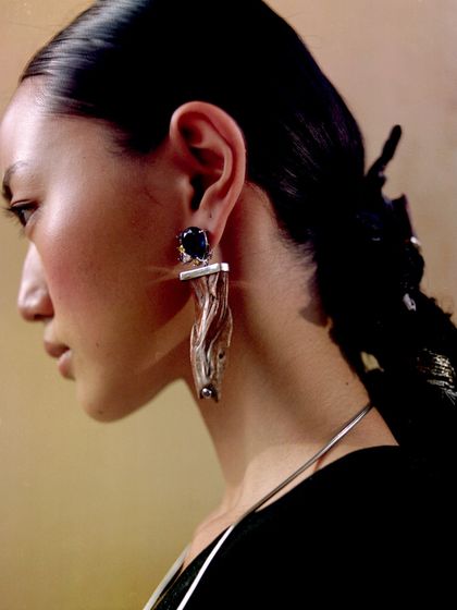 A portrait showcasing the sculptural silver earrings from the Ani Clothing shoot.